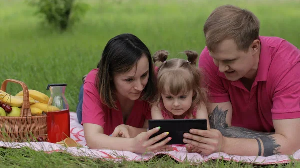 Családi hétvégi piknik. Lány gyermek lány anya és apa néz online filmeket tabletta — Stock Fotó