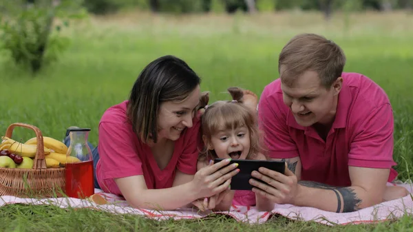 Családi hétvégi piknik. Lány gyermek lány anya és apa játék online játékok tabletta — Stock Fotó