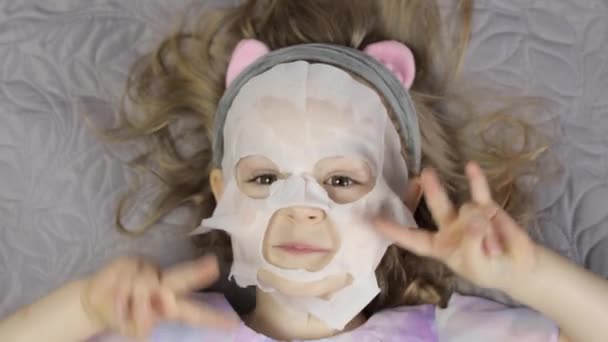 Adolescente ragazza che applica maschera idratante. Bambino bambino prendersi cura della pelle con maschera facciale cosmetica — Video Stock