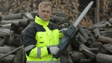 Yansıtıcı ceketli oduncu. Elektrikli testereli oduncu. Testere kütükleri, yakacak odun, kereste fabrikası