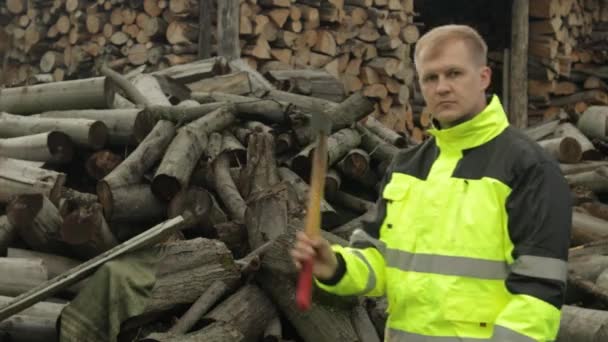 Lumberjack en chaqueta reflectante. Hombre leñador con hacha pequeña. Troncos aserrados, fondo de leña — Vídeos de Stock