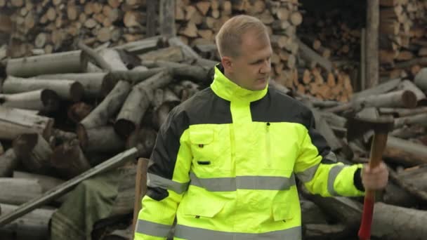 Lumberjack en chaqueta reflectante. Hombre leñador sostiene hachas pequeñas y grandes en sus manos. Leña — Vídeos de Stock