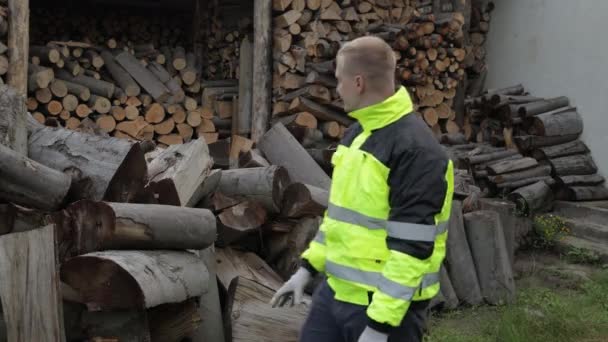 Holzfäller in reflektierender Jacke. Mann Holzfäller zeigen ok Zeichen. Schnittholzstämme, Brennholz Hintergrund