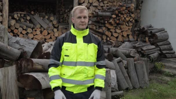 Lumberjack in reflective jacket. Man woodcutter show thumbs up. Sawn logs, firewood background — Stock Video