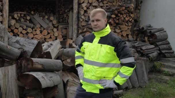 Lumberjack in reflective jacket. Man woodcutter show thumb up. Sawn logs, firewood background — Stock Video