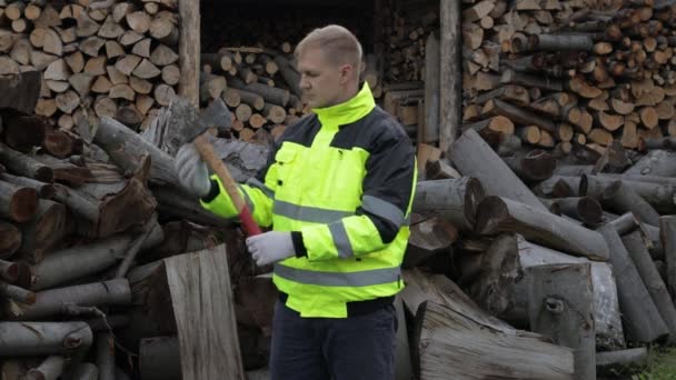 Lumberjack en chaqueta reflectante. Hombre leñador con hacha pequeña. Troncos aserrados, fondo de leña — Vídeos de Stock