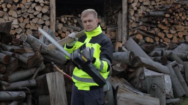 Skogshuggare. Man träskärare håller stor yxa och elektrisk motorsåg på händerna. Ved — Stockvideo