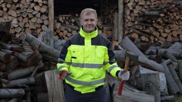 Lumberjack en chaqueta reflectante. Hombre leñador sostiene hacha pequeña y vio en sus manos. Leña — Vídeos de Stock