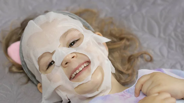 Teen girl applying moisturizing face mask. Child kid take care of skin with cosmetic facial mask — Stock Photo, Image