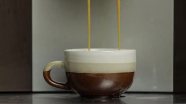 Kahve makinesinden küçük beyaz ve kahverengi bardakta espresso fışkırıyordu. Görüntüleri kapat
