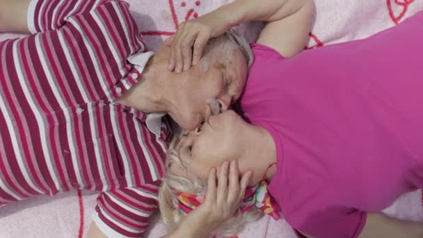 Family weekend picnic. Senior old caucasian couple lie on blanket facing each other, making a kiss — Stock Video