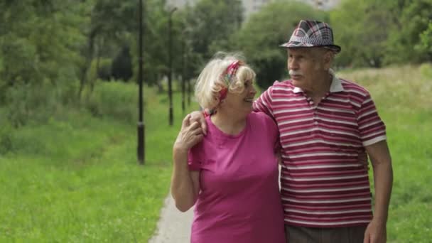 Coppia caucasica anziana che cammina nel parco abbracciando. L'uomo anziano cammina con la donna. Marito, moglie — Video Stock