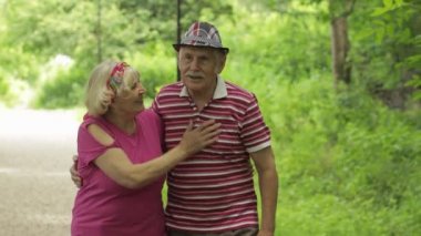 Kıdemli beyaz çift parkta kucaklaşarak yürüyor. Yaşlı adam bir kadınla yürüyor. Karı koca.