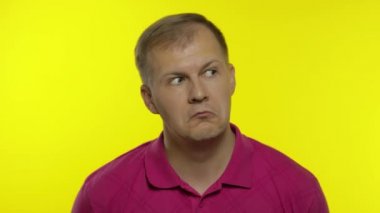 Pembe tişörtle poz veren beyaz bir gencin portresi. Kafası karışmış yakışıklı adam şaşırmış, şaşırmış.
