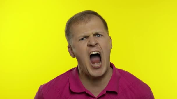 Egy fiatal fehér férfi portréja rózsaszín pólóban. Jóképű srác sikoltozik és dühös lesz. — Stock videók