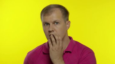 Pembe tişörtle poz veren beyaz bir gencin portresi. Endişeli yakışıklı adam şok, korkmuş, korkmuş