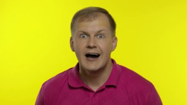 Pembe tişörtle poz veren beyaz bir gencin portresi. Tatmin olmuş yakışıklı adam kutluyor, kazanıyor.