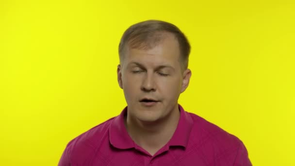 Portret van een jonge blanke man die poseert in een roze t-shirt. Ontevreden man legt hand op gezicht, facepalm — Stockvideo