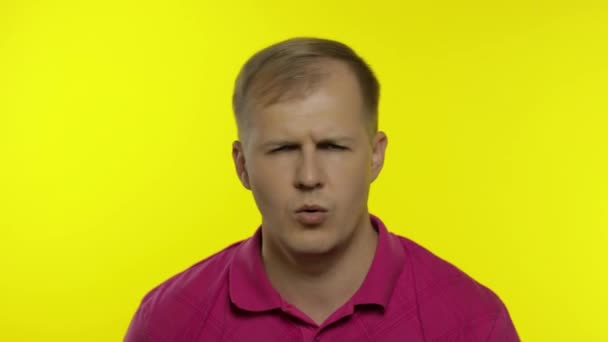 Portrait of young caucasian man posing in pink t-shirt. Dissatisfied guy puts hand on face, facepalm — Stock Video