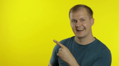 Yeşil tişörtlü genç bir adamın portresi. Mutlu gülümseyen adam elinde bir şeyi işaret ediyor.