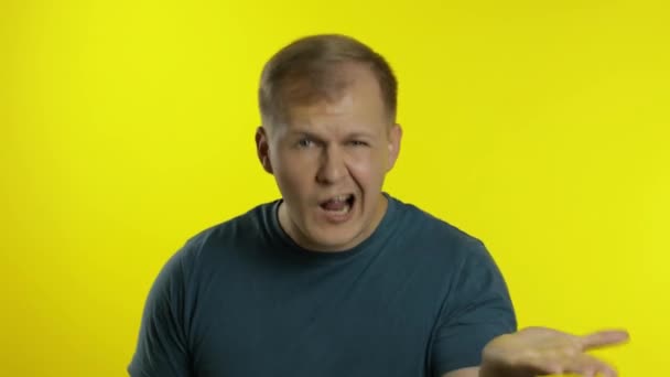 Portrait of young man posing in green t-shirt. Angry dissatisfied guy quarrels, waves his hands — Stock Video