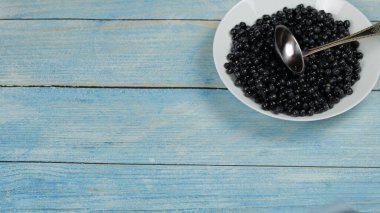 Mavi ahşap masa zemininde beyaz böğürtlenler içinde nefis taze yaban mersinleri. Üst görünüm