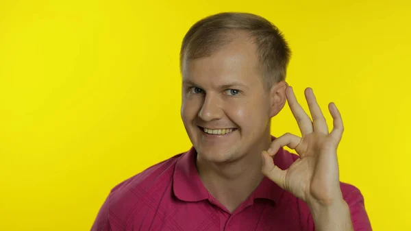 Portret van een blanke man die poseert in een T-shirt. Een glimlachende knappe man toont een goed teken. Mensen emoties — Stockfoto