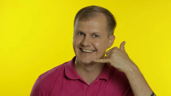 Retrato de homem posando em camiseta rosa. Cara feliz pedindo para ligar para ele, mostra o telefone com a mão — Fotografia de Stock