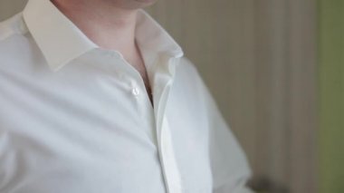 Damat beyaz gömleğini düzeltiyor. Düğün sabahı. İş adamı. Ağır çekim. Yakın plan çekim. Portre