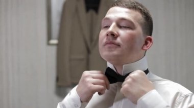 Damat papyonu ayarlar. Geline gitmeye hazırlanıyor. Beyaz gömlekli bir iş adamı. Düğün günü.