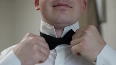 Damat papyonu ayarlar. Geline gitmeye hazırlanıyor. Beyaz gömlekli bir iş adamı. Düğün günü.