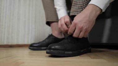 Damat düğün gününde düğün ayakkabılarını giyiyor. Damadın elleri.