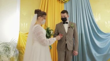 Yeni evliler. Gelin ile beyaz damat, nikah töreninde yüzükleri değiş tokuş ediyor. Coronavirus covid-19
