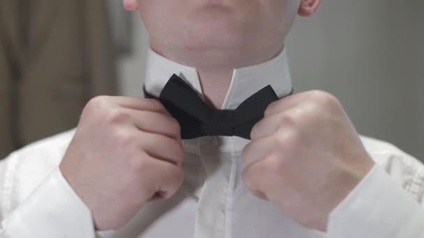 新郎は、蝶ネクタイを調整します。花嫁に行く準備をする。白いシャツを着たビジネスマン。結婚式日 — ストック動画