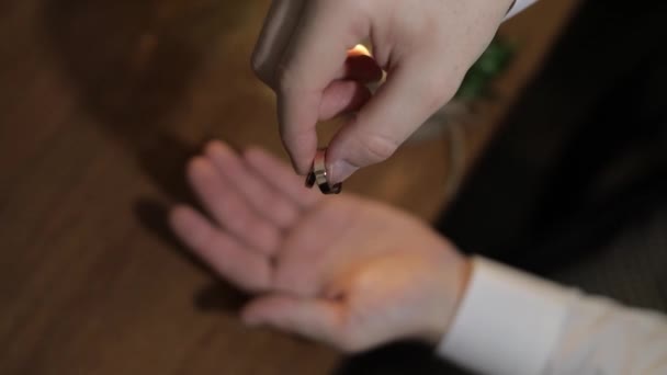 Un novio con una camisa blanca deja caer anillos de bodas en la palma de su mano. El hombre toca los anillos — Vídeo de stock