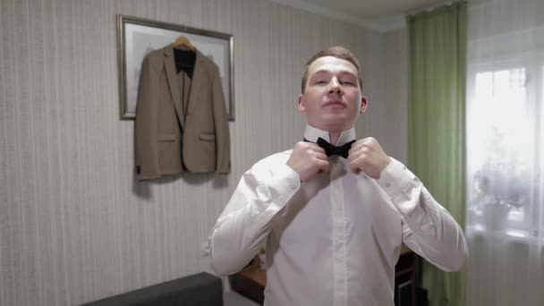 新郎は、蝶ネクタイを調整します。花嫁に行く準備をする。白いシャツを着たビジネスマン。結婚式日 — ストック動画