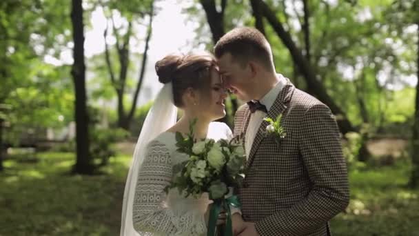Yeni evliler. Gelin ile beyaz damat parkta yürüyor, sarılıyor, sarılıyor. Düğün çifti — Stok video