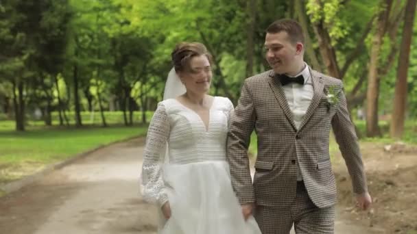 Recién casados. El novio caucásico con novia corre en el parque. Pareja de bodas. Hombre y mujer enamorados — Vídeos de Stock