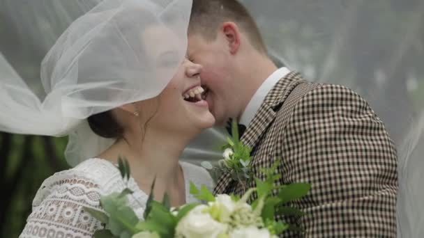 Newlyweds. Caucasian groom with bride stay under veil in park. Wedding couple. Man and woman in love — Stock Video