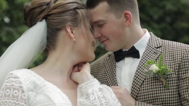 Frisch verheiratet. Kaukasischer Bräutigam mit Braut beim Gehen, Umarmungen, Umarmungen im Park. Hochzeitspaar — Stockvideo