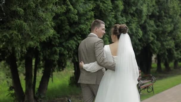 Yeni evliler. Beyaz damat ve gelin parkta yürüyor. Düğün çifti. Aşık bir adam ve kadın — Stok video