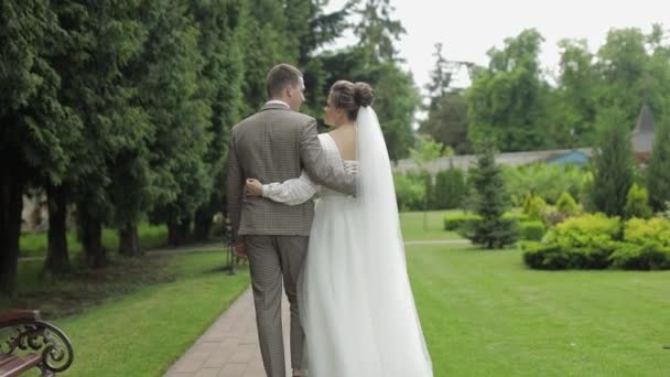 Recién casados. novio caucásico con novia caminando en el parque. Pareja de bodas. Hombre y mujer enamorados — Vídeos de Stock