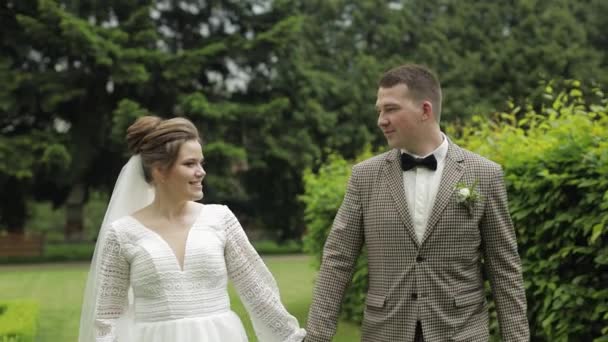 Friss házasok. Fehér vőlegény, menyasszony sétál a parkban. Esküvői pár. Szerelmes férfi és nő — Stock videók