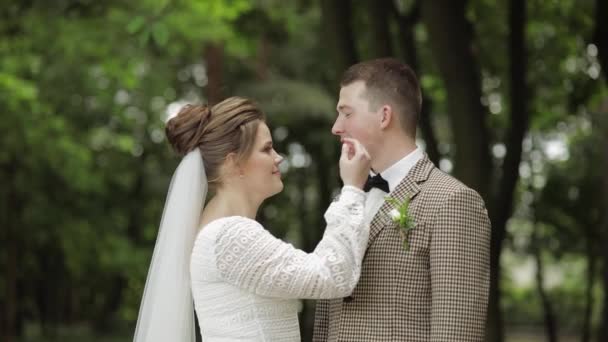 Recién casados. novio caucásico con novia haciendo un beso en el parque. Pareja de bodas. Hombre y mujer enamorados — Vídeos de Stock