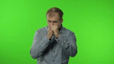 Komik yakışıklı adam kameraya karşı dövüşmeye çalışıyor, ifadeyle boks yapıyor. Krom anahtar arkaplanındaki adam