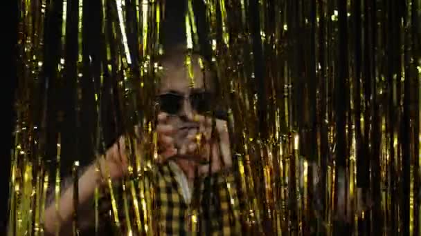 Portrait of caucasian man posing on black background. Gold shining foil strips. Party, music, disco — Stock Video