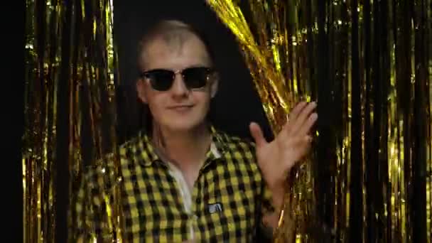 Siyah arka planda poz veren beyaz bir adamın portresi. Altın parlayan folyo şeritleri. Parti, müzik, disko — Stok video