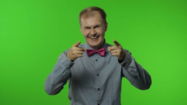 Kameraya gülümseyen, kaygısız gülen, kamerayı işaret eden, bir şey seçen mutlu bir adam.