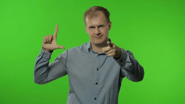 Guy showing loser gesture, pointing finger to camera, sarcastic smile, blaming for failure, lost job