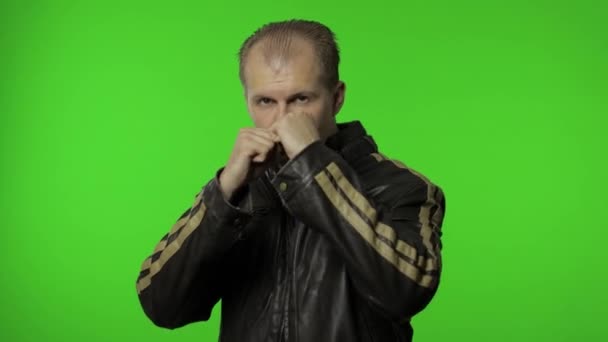 Rolig rockare man i brun denim jacka försöker slåss vid kameran, boxning med uttryck — Stockvideo